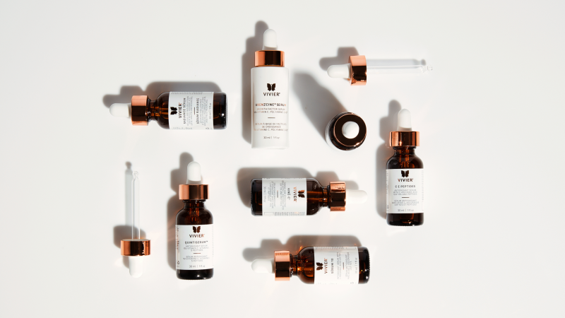 A group of vitamin C serums arranged tastefully on a white backdrop.